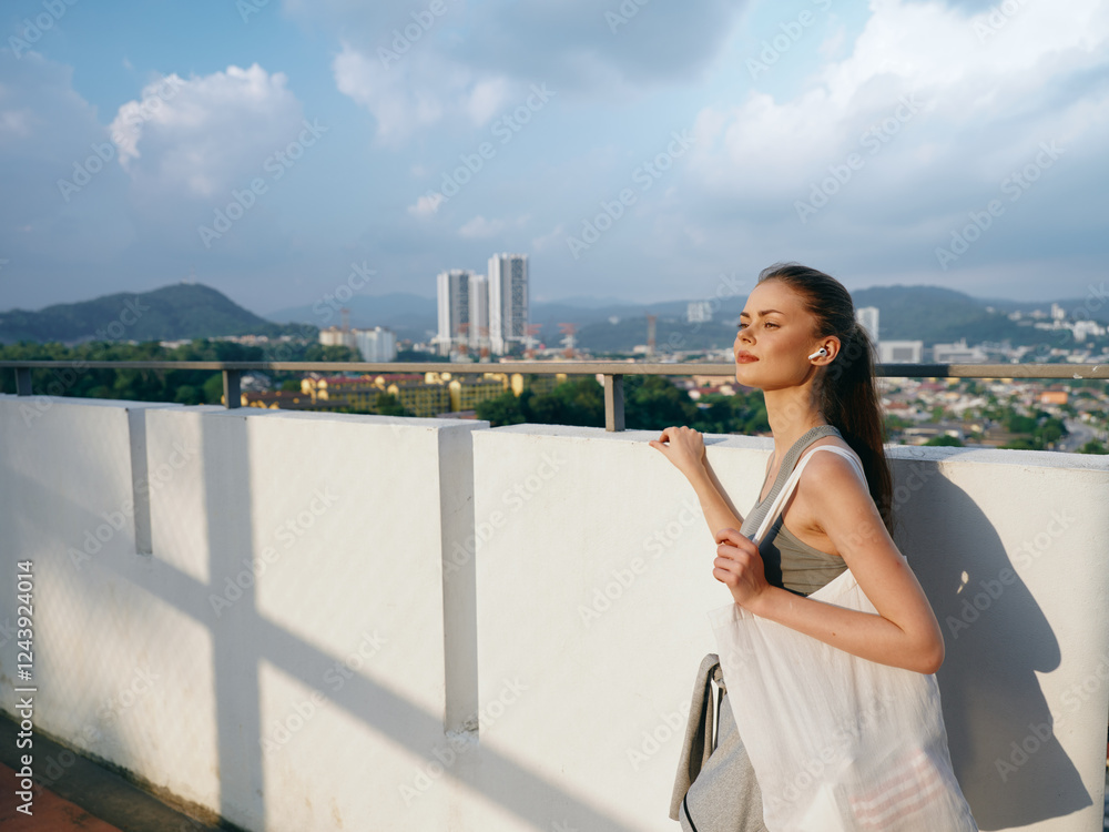 Woman enjoying the view on a rooftop terrace with city skyline in the background and clouds above Woman enjoying the view on a rooftop terrace with city skyline in the background and clouds above