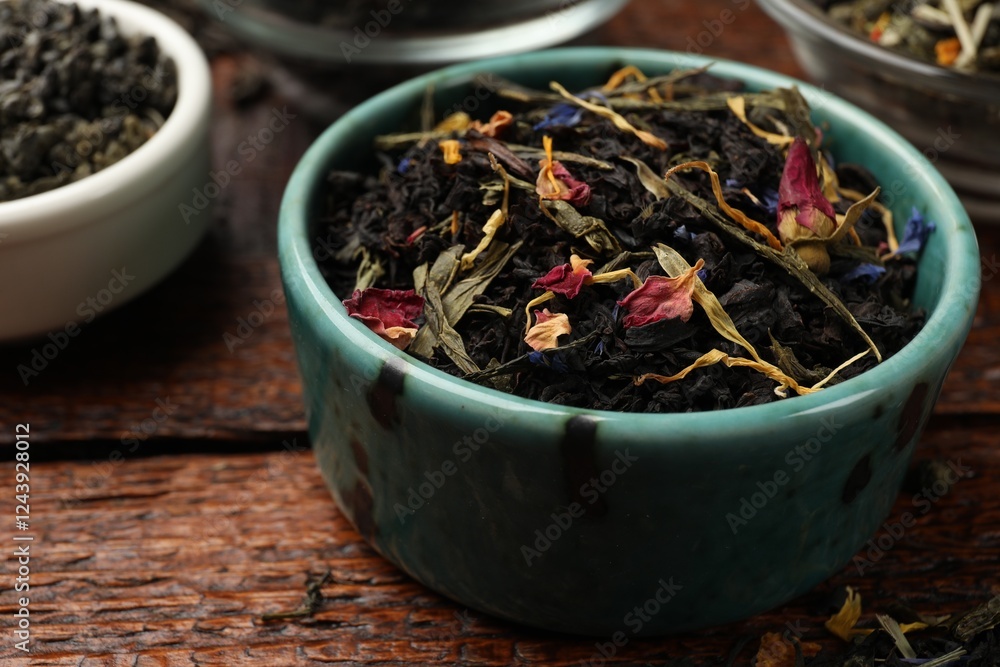 Different dry tea leaves in bowl on wooden table, closeup Different dry tea leaves in bowl on wooden table, closeup