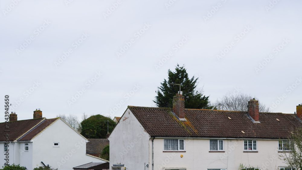 Traditional English rooftops in a suburban neighborhood under cloudy skies Traditional English rooftops in a suburban neighborhood under cloudy skies