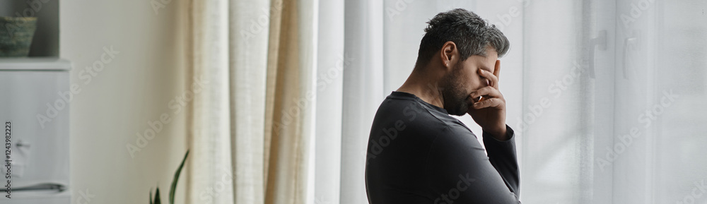 Contemplative moment of a handsome man standing by a window in soft natural light