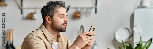 Fényképezés Handsome man enjoys leisure time while checking his phone in a cozy kitchen sett