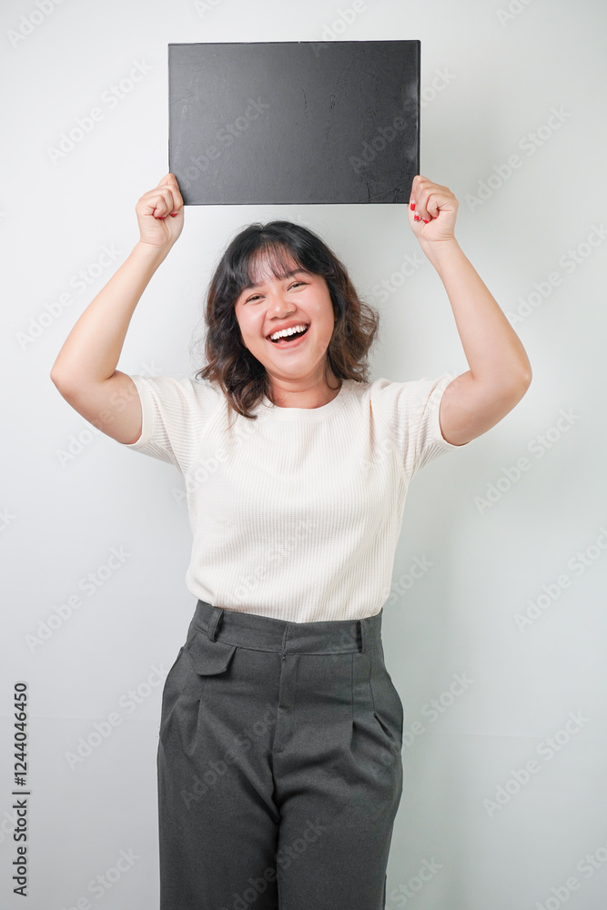 Beautiful young asian woman with wavy hair wearing white shirt holding a black blank square board, isolated over white background. Beautiful young asian woman with wavy hair wearing white shirt holding a black blank square board, isolated over white background.