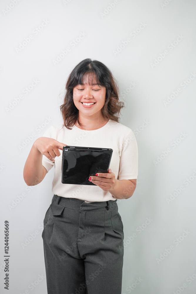 Beautiful young asian woman with wavy hair wearing white shirt holding a tablet, isolated over white background. Beautiful young asian woman with wavy hair wearing white shirt holding a tablet, isolated over white background.