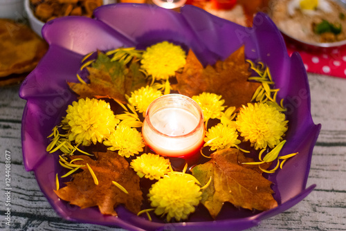 Diwali decor with floating candle, yellow flowers, and autumn leaves. photo