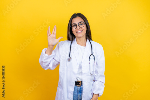 Fotografi Young brunette doctor woman wearing stethoscope standing over isolated yellow ba
