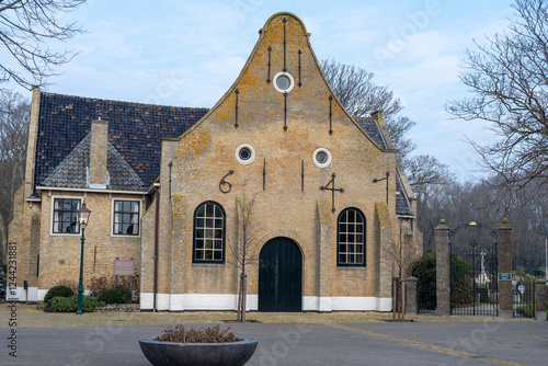 Front view of the historic Nicolaaskerk (1647) on Vlieland, with its facade lettering and gate to the Commonwealth War Graves, captured on a clear, bright day photo