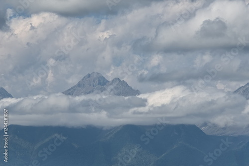 Russia. The Republic of Buryatia. Scenic view of the peaks of the Eastern Sayan mountain range drowning in fog and cumulus clouds from the valley of the Irkut River. photo