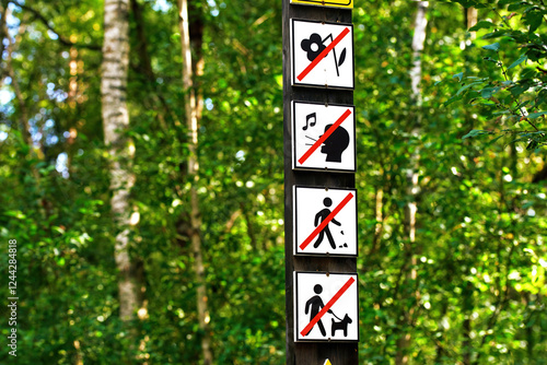 Eco trail regulation signboard in green forest environment, restrictions like no pets, no flower picking, littering, loud noises, with directional sign pointing towards wild horse trail 0.5 km ahead