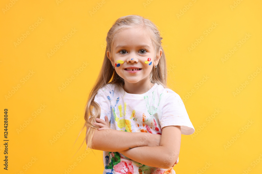 Smiling girl with crossed arms smeared in paint on orange background