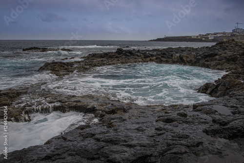 Dramatic coastal scene in Gran Canaria with waves crashing against dark volcanic rocks. El Bufadero