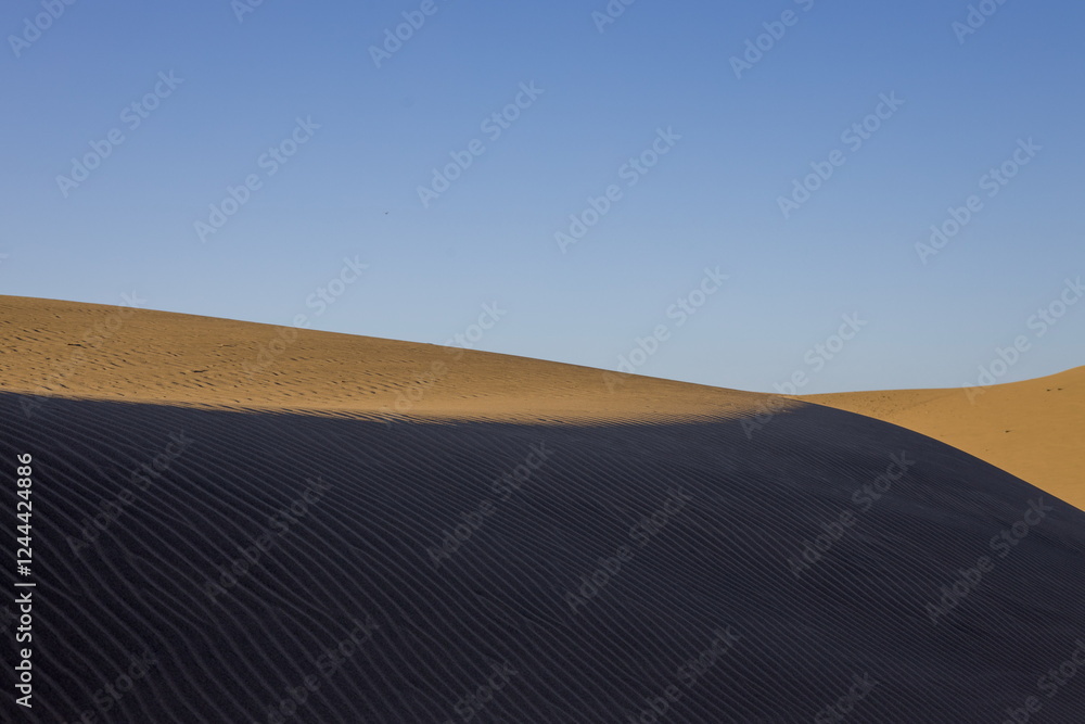 Maspalomas Dunes in Gran Canaria. Textured sand dunes with patterns, shadows, and faint footprints.