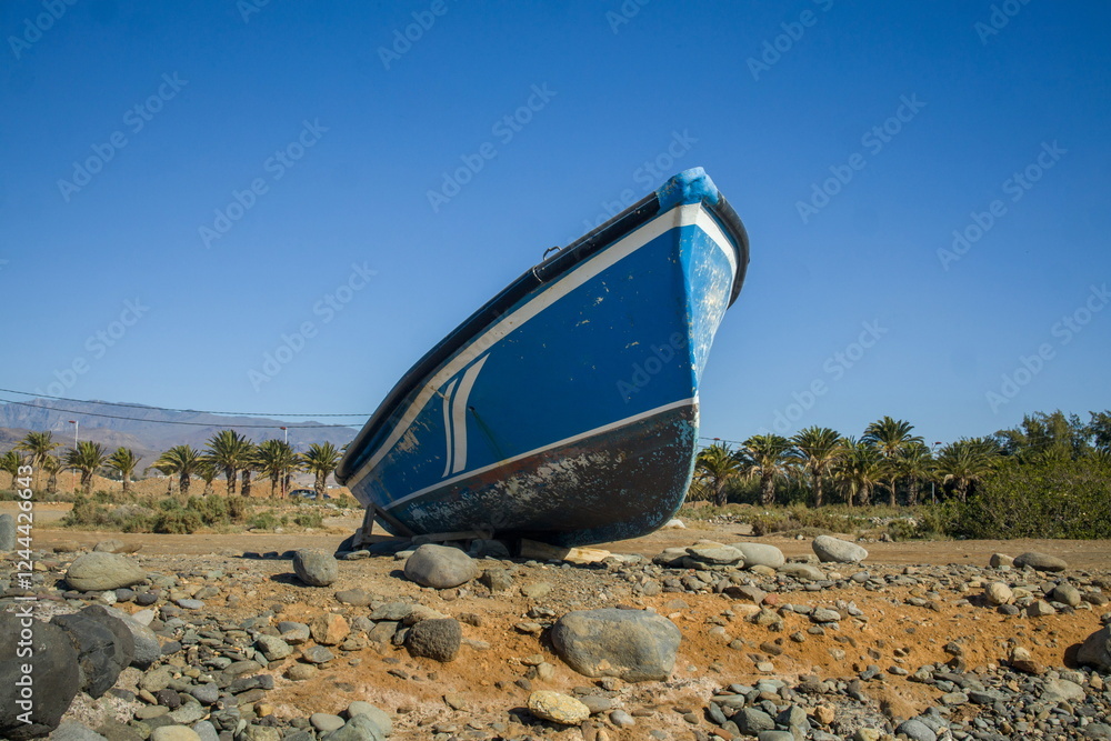 Small, blue boat on a rocky beach.
