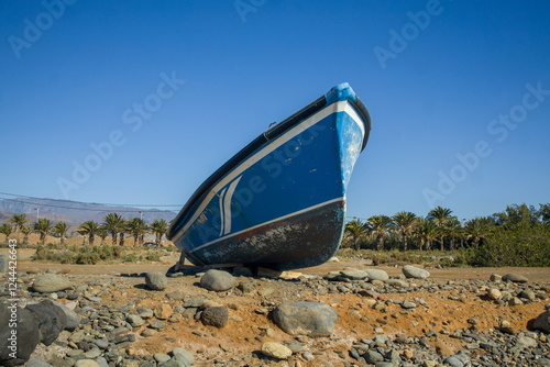 Obraz na płótnie Small, blue boat on a rocky beach. w salonie