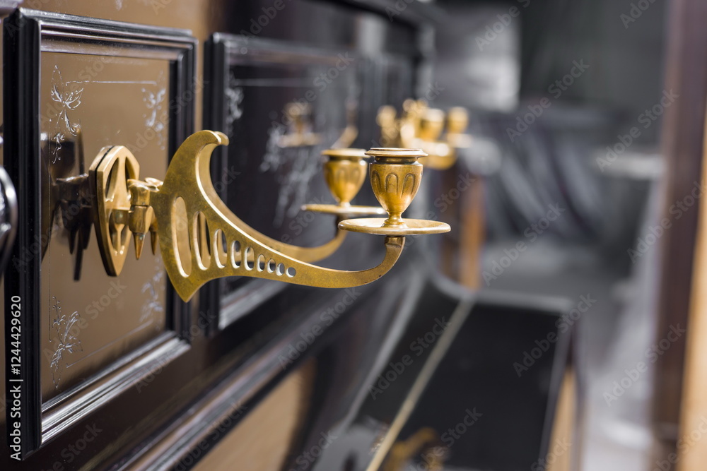 Close-up of a grand piano with ornate, golden ormolu candle holders.
