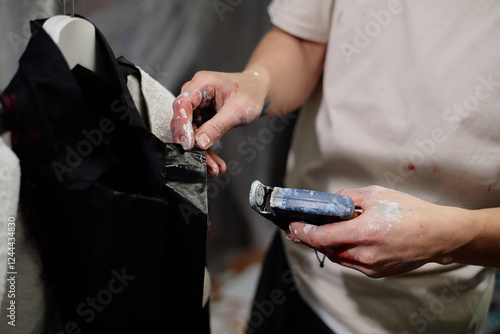 Cropped shot of male fashion artist fixating details on custom made jacket using staple gun in workshop, copy space photo