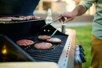 Man grilling hamburgers and steaks on backyard grill