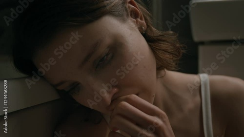 Close-up shot of miserable young woman with mascara smudged under her eyes because of crying sitting on floor in bathroom