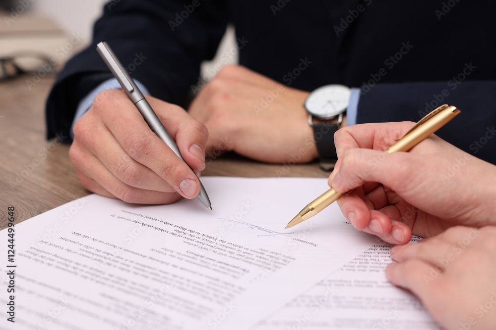 Woman pointing at document and man putting signature at table, closeup Woman pointing at document and man putting signature at table, closeup