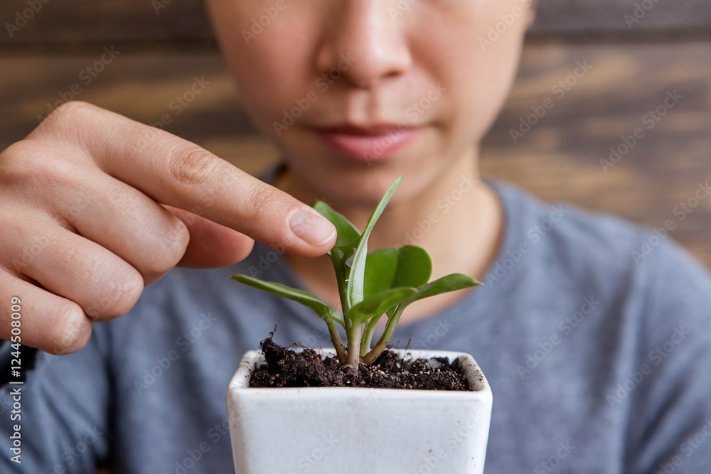 Nurturing a Young Plant: A Close-Up of Care and Growth. A person gently touches a small potted plant, symbolizing nurturing and growth. The focus is on the connection between human and nature. Nurturing a Young Plant: A Close-Up of Care and Growth. A person gently touches a small potted plant, symbolizing nurturing and growth. The focus is on the connection between human and nature.