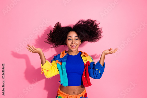 Young woman in colorful denim while gesturing happily on pink backdrop photo