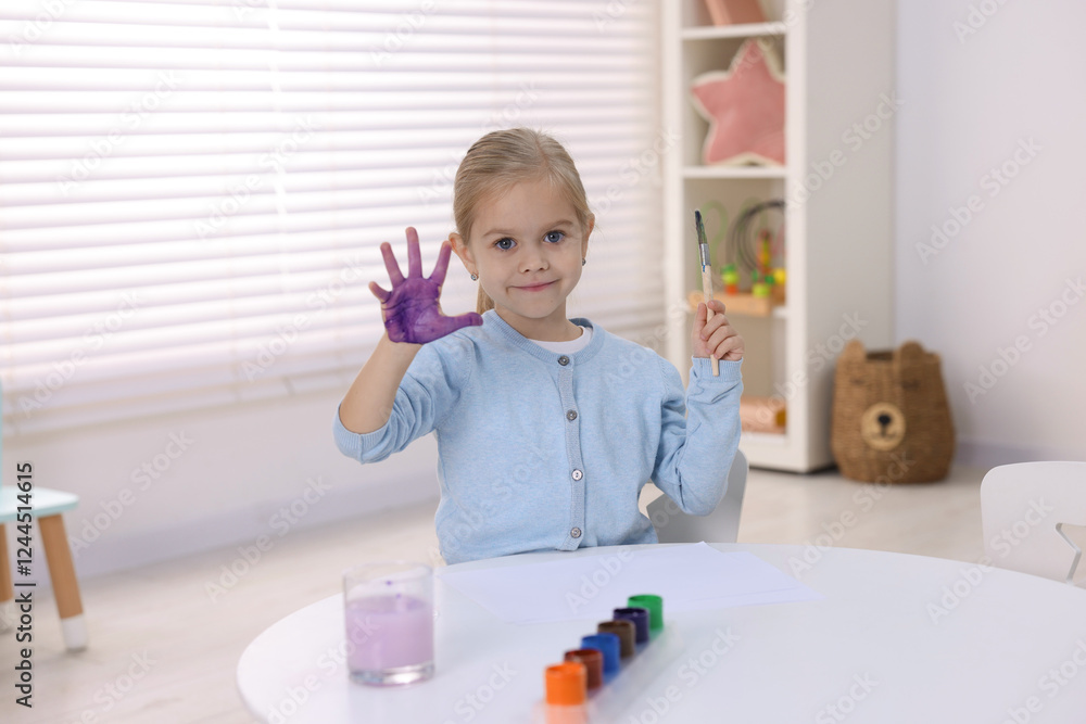 Cute girl drawing with palm at white table in kindergarten Cute girl drawing with palm at white table in kindergarten