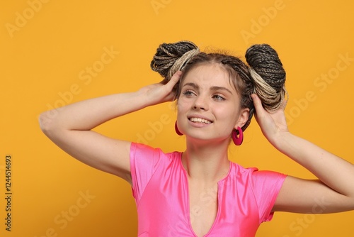 Beautiful woman with braided double buns on yellow background