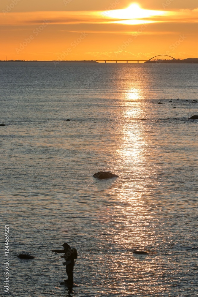 Fligenfischen auf Meerforelle auf der Ostseeinsel Fehmarn am Riff von Staberhuk mit Fehmarn Sund Brücke im Hintergrund.