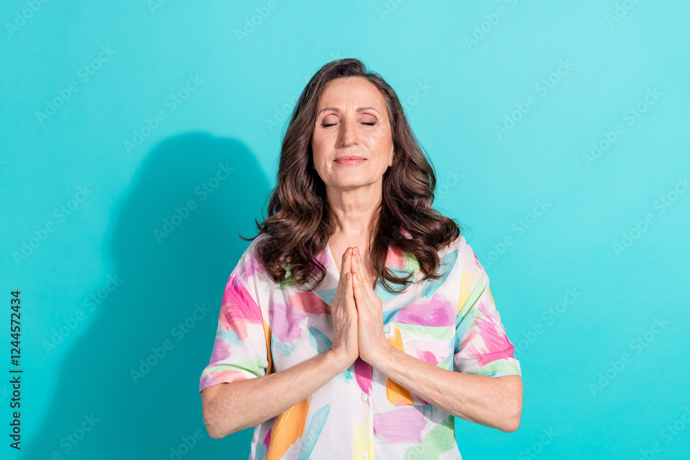 Photo portrait of pretty retired female pray gesture closed eyes wear trendy colorful outfit isolated on cyan color background Photo portrait of pretty retired female pray gesture closed eyes wear trendy colorful outfit isolated on cyan color background