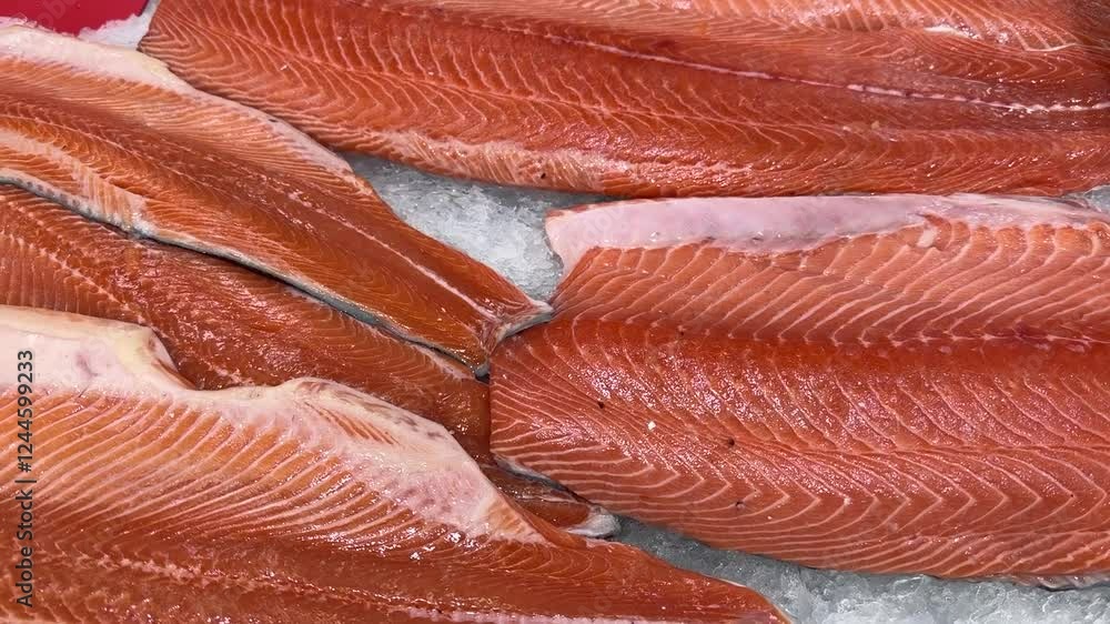 Raw fresh layers of Atlantic salmon lie on shallow ice at the seafood market. An open shelf at the fish market. Close-up Raw fresh layers of Atlantic salmon lie on shallow ice at the seafood market. An open shelf at the fish market. Close-up