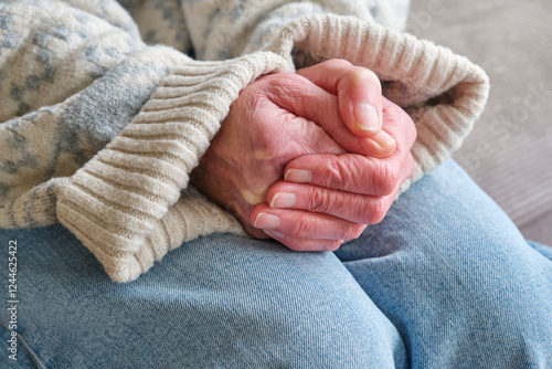 Closeup of the red cold hands of a caucasian woman trying to get wam in a thick knitted sweater in winter. Cold weather, energy crisis and high energy prices concept.	