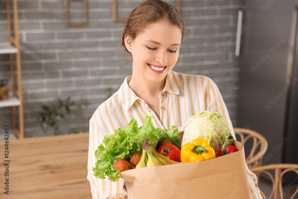 Young woman with paper bag of healthy food in kitchen Young woman with paper bag of healthy food in kitchen