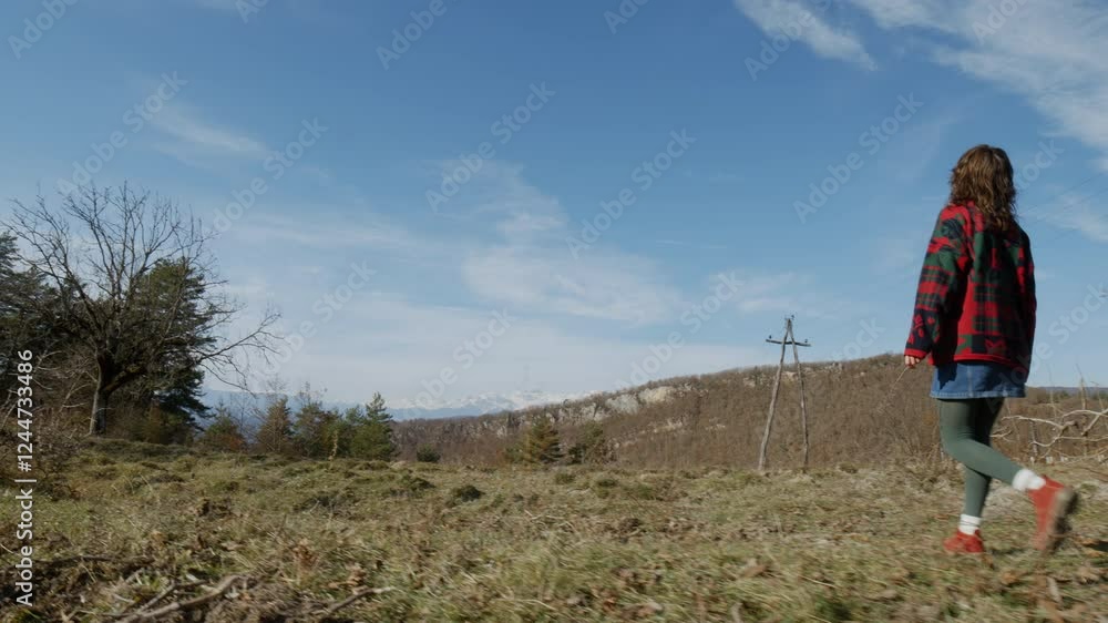 Person Walking Through Beautiful Nature, Mountains on the Horizon Under a Blue Sky Person Walking Through Beautiful Nature, Mountains on the Horizon Under a Blue Sky