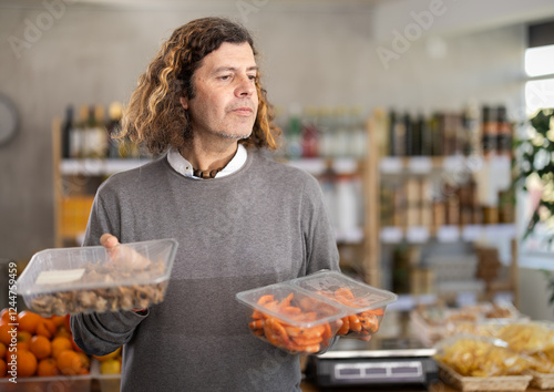 Adult male choosing oceanic shrimp and mollusks Bolinus brandaris, he looks at the packaging and the date of manufacture of the product photo