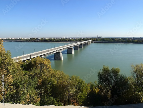 Wallpaper Mural Long bridge spans a wide river with a cityscape visible in the distance on a clear day. Torontodigital.ca