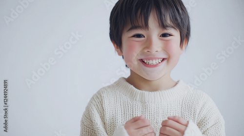 Obraz na płótnie 両手で小さくガッツポーズしている笑顔な小学生の男の子 背景白いスタジオ w salonie