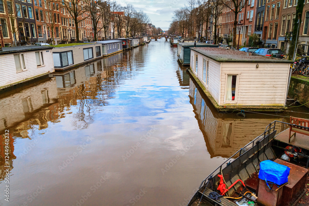 Cityscape on a sunny winter day - view of the water canal with houseboats in the historic center of Amsterdam, the Netherlands