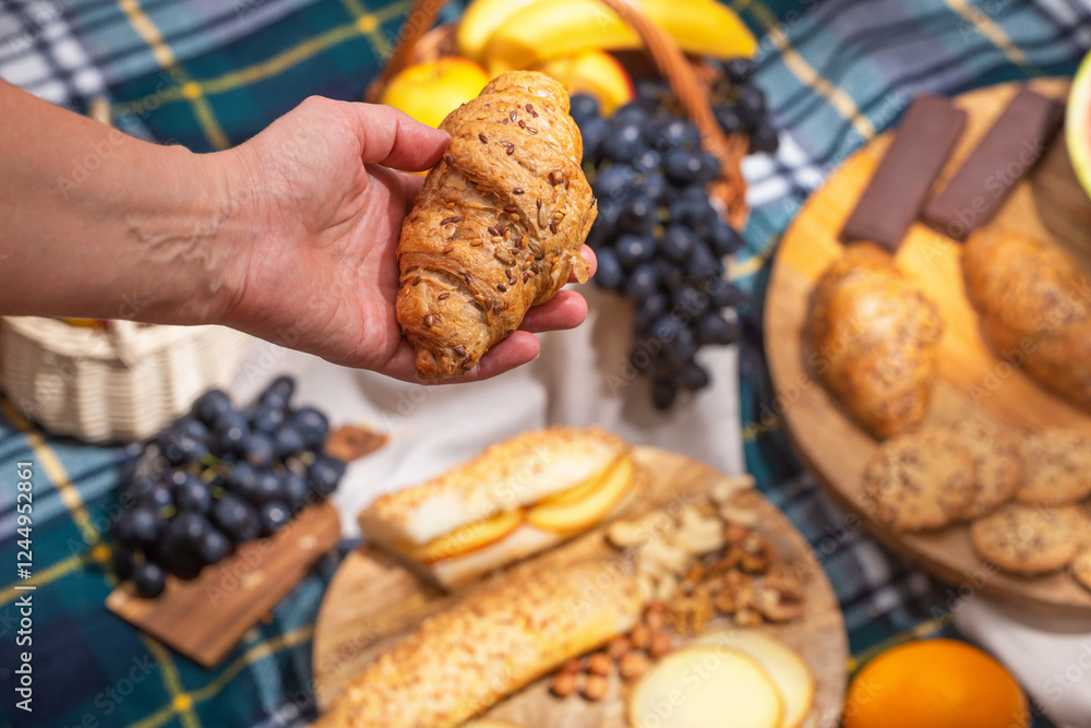 Close-up view of a picnic with food laid out and hands holding food, selective focus. The concept of summer outdoor recreation on the weekend