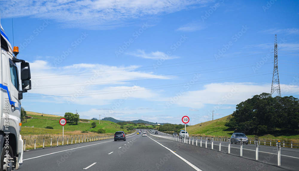 Truck driving on Waikato Expressway. 110 km/h road speed signs by the side of motorway. New Zealand.