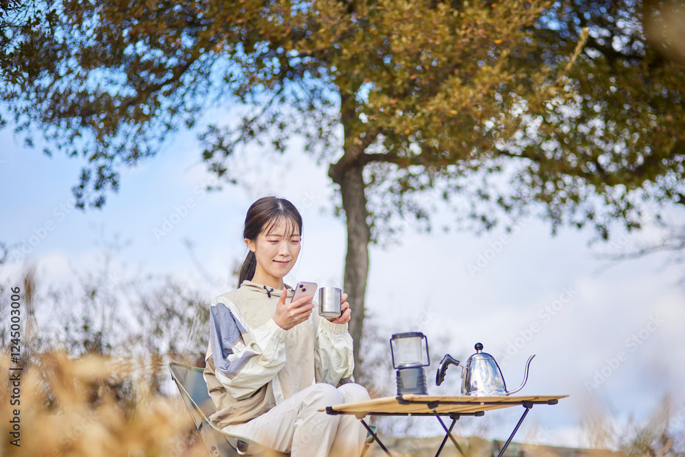 Fototapeta premium 冬の山でアウトドアを楽しみながらスマートフォンを使う日本人女性