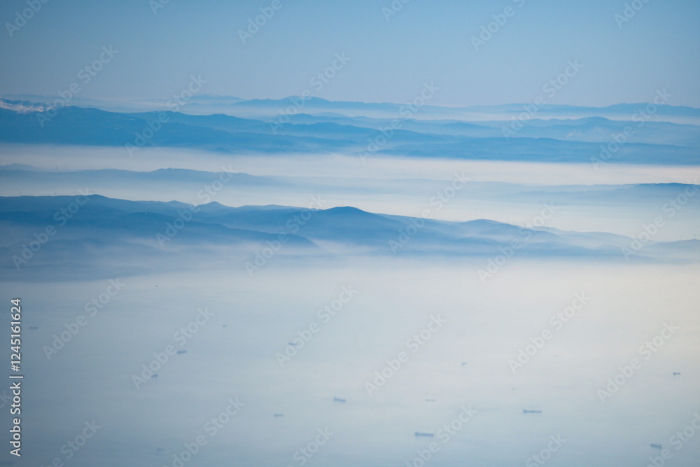 Misty mountains and distant ships under a serene blue sky Misty mountains and distant ships under a serene blue sky