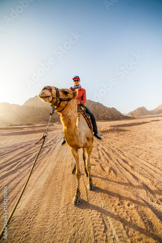 Fotografia A man riding a camel in Sharm El-Sheikh, Egypt.