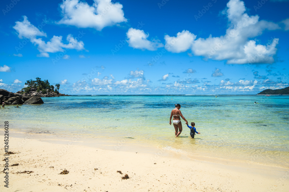 Asian woman with child walking hand in hand to the sea, Seychelles Asian woman with child walking hand in hand to the sea, Seychelles
