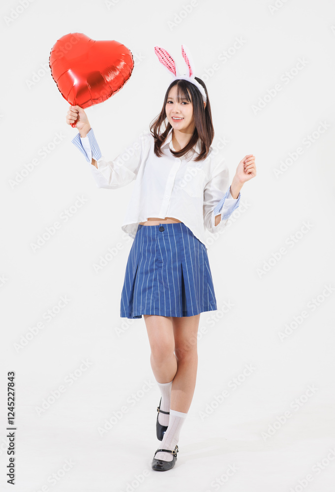 Portrait happy Asian young pretty woman wearing casual clothes bunny rabbit ears, teenager funny holding balloon heart shape color red smiling while standing pose on white background, Easter concept. Portrait happy Asian young pretty woman wearing casual clothes bunny rabbit ears, teenager funny holding balloon heart shape color red smiling while standing pose on white background, Easter concept.