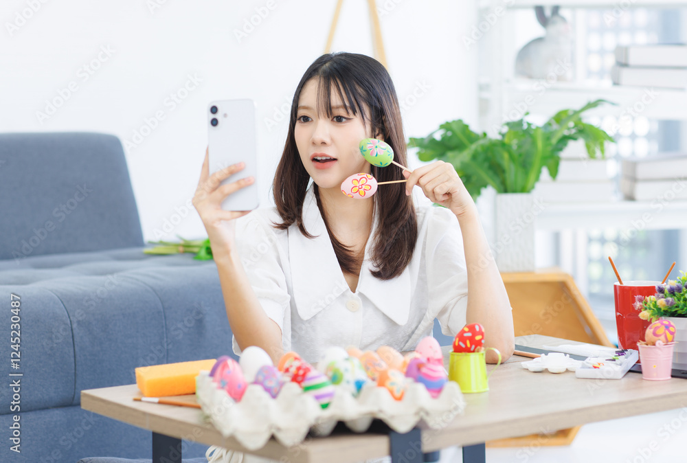 Asian beautiful attractive cheerful young cute lovely sweet woman taking selfie with mobile phone happy funny painting eggs sitting in the living room at home, prepare for Easter celebration concept. Asian beautiful attractive cheerful young cute lovely sweet woman taking selfie with mobile phone happy funny painting eggs sitting in the living room at home, prepare for Easter celebration concept.