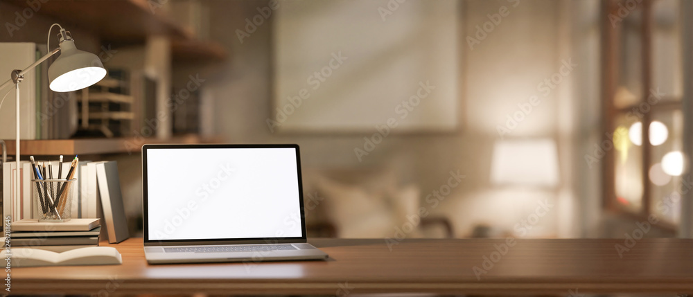 A close-up of a laptop and stationery on a wooden desk, illuminated by a table lamp. A close-up of a laptop and stationery on a wooden desk, illuminated by a table lamp.