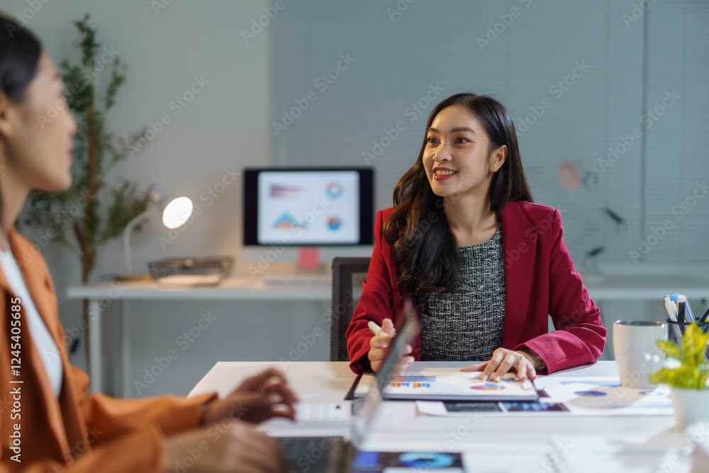 Asian businesswomen working together analyzing financial charts at office desk Asian businesswomen working together analyzing financial charts at office desk