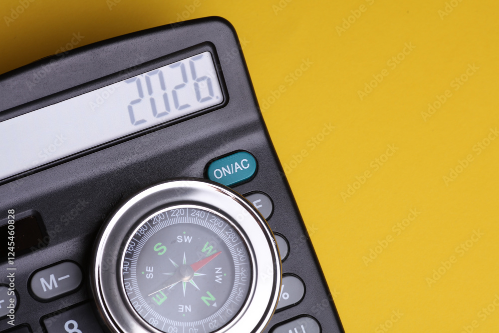Calculator with number 2026 and compass on yellow background. Economic analysis, budget of the year Calculator with number 2026 and compass on yellow background. Economic analysis, budget of the year