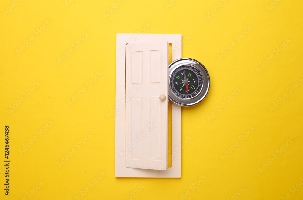 Miniature wooden door with compass on yellow background Miniature wooden door with compass on yellow background