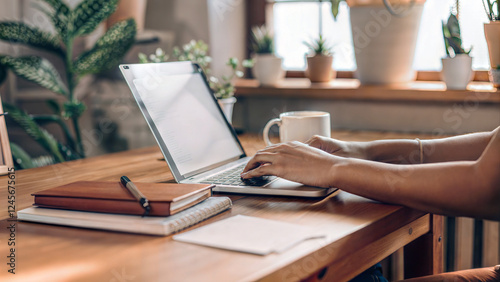 Wallpaper Mural Remote worker typing laptop minimalist wooden desk sunlit home office plants notebooks mug productivity Torontodigital.ca