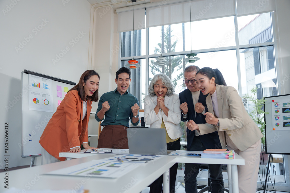 Obraz premium Diverse team of business professionals is cheering and celebrating their success while looking at a laptop in a modern office, showing their excitement and teamwork